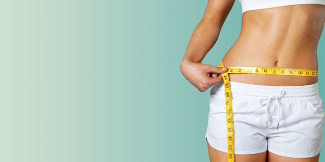 Slim young woman measuring her thin waist
